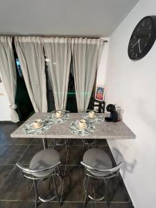 einen Tisch mit zwei Stühlen und eine Uhr an der Wand in der Unterkunft Sun Beach Arinaga in Arinaga