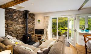 a living room with a fireplace and a stone wall at Pennys Cottage in Troutbeck