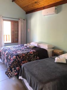a bedroom with two beds and a window at Chales Sao Felix in Paiol Grande