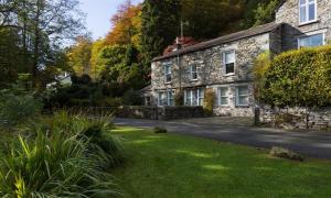 an old stone house with a driveway in a yard at The Mews in Ambleside