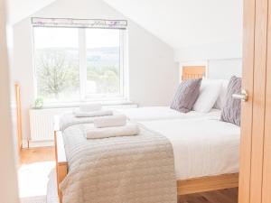 a white bedroom with two beds and a window at Cedar Wood Coniston in Coniston