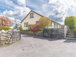 a house with a fence and a stone wall at Cedar Wood Coniston in Coniston