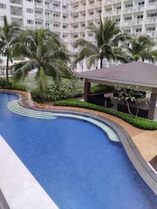 - une piscine dans un complexe avec des palmiers dans l'établissement Shore residences, à Manille