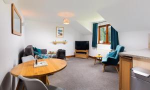 a living room with a table and chairs and a tv at High Dow Crag in Coniston