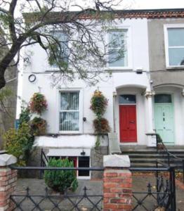 a white house with a red door on a street at Eglinton Road - Sleeps 6 on room only basis in Bray