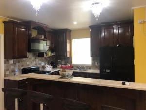 a kitchen with wooden cabinets and a black refrigerator at palmvillo master suit 