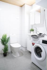 a white bathroom with a washing machine and a toilet at Lovely Northern Apartment in Oulu