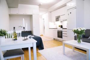 a white living room with white tables and a kitchen at Lovely Northern Apartment in Oulu