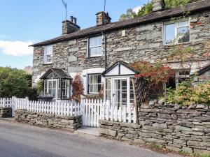 an old stone house with a white picket fence at Weir Cottage in Ambleside +13 photos