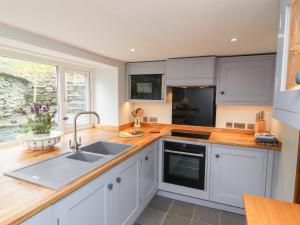una cocina con armarios blancos y fregadero en Weir Cottage, en Ambleside