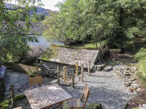 un jardín con una mesa, bancos y un estanque en Weir Cottage, en Ambleside