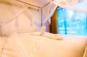 Una cama blanca con un par de toallas. en บ้านสวีทคาบาน่า และบ้านสวีทโอโซนBy The mountain Ozone บ้านโอโซนขุนเขาแก่งกกระจาน en Ban Song Phi Nong