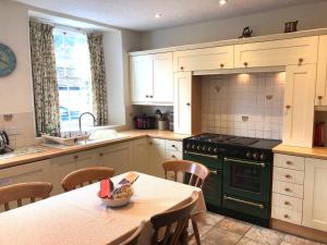 cocina con mesa y estufa verde horno superior en White Lion Cottage en Chapel Stile