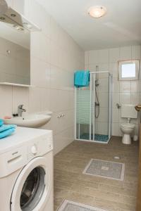 een wasmachine in een badkamer met een wastafel en een douche bij Family friendly house with a swimming pool Cista Velika, Vodice - 20234 in Velika Čista