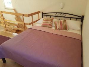 Schlafzimmer mit einem Bett mit lila Bettwäsche und Kissen in der Unterkunft Holiday house with a parking space Milna, Brac - 20140 in Milna