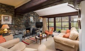 a living room with a stone wall with a fireplace at Thirlmere Cottage in Keswick