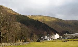 a village in front of a mountain with houses and trees at Thirlmere Cottage in Keswick