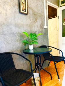 - une table avec deux chaises et une plante en pot dans l'établissement บ้านสวีทคาบาน่า และบ้านสวีทโอโซนBy The mountain Ozone บ้านโอโซนขุนเขาแก่งกกระจาน, à Ban Song Phi Nong