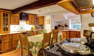 een keuken met houten kasten en een tafel met stoelen bij High Cleabarrow in Windermere
