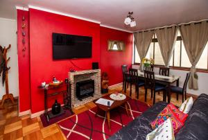 sala de estar con pared roja y comedor en Departamento Freire, en Valparaíso