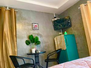 Cette chambre comprend un réfrigérateur vert et 2 chaises. dans l'établissement บ้านสวีทคาบาน่า และบ้านสวีทโอโซนBy The mountain Ozone บ้านโอโซนขุนเขาแก่งกกระจาน, à Ban Song Phi Nong
