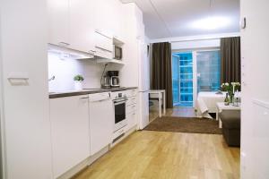 a kitchen with white cabinets and a living room at City center 1R studio with perfect view, parking in Oulu