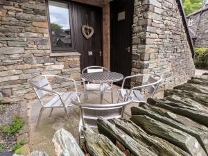une terrasse avec 2 chaises et une table sur une maison dans l'établissement Babbling Brook, à Ambleside
