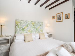 - une chambre blanche avec un grand lit blanc et des oreillers dans l'établissement School Cottage, à Ambleside