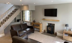 a living room with a couch and a fireplace and a television at Gale Mews in Ambleside