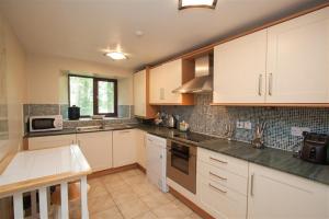 a kitchen with white cabinets and a table in it at Over Ghyll in Ambleside