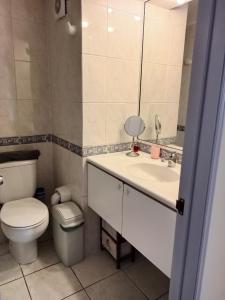 a bathroom with a toilet and a sink with a mirror at Espectacular Departamento frente al mar in Antofagasta