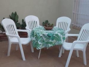 a table with four white chairs and a plant on it at Aguaribay in Chivilcoy
