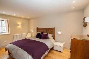 a bedroom with a large bed with purple pillows at Sunny Brow Barn in Ambleside