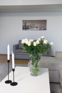 a vase of white roses on a table with two candles at 4-room apartment. Oulu city center in Oulu