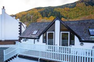 een wit huis met een balkon en een berg bij Cygnet Cottage in Keswick