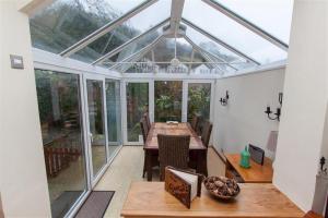 a conservatory with a table and a glass roof at Little Brook in Ambleside