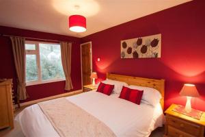 1 dormitorio con paredes rojas y 1 cama blanca con almohadas rojas en Little Brook, en Ambleside