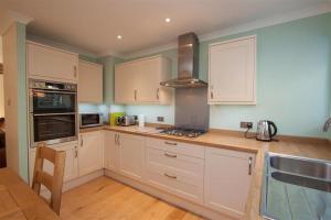 a kitchen with white cabinets and a stove top oven at Beckside in Ambleside