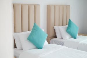 two twin beds with blue pillows in a room at Sunrise by white sand dhigurah in Dhigurah