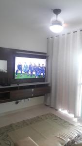 een woonkamer met een tv met een voetbalspel erop bij Residencial Santos Dumont in Mongaguá