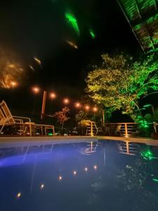 イリャベラにあるSOL&MAR Suítes Ilhabelaの緑の照明が灯る夜のスイミングプール