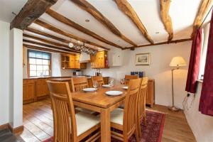 Il comprend une cuisine et une salle à manger avec une table et des chaises en bois. dans l'établissement Lowfold Cottage, à Ambleside