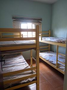 three bunk beds in a room with a window at Pousada Caminho da Serra in Ubatuba