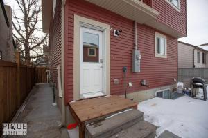 a white door on a red house with a bench at NEW, Mountain Chic Suite, Whyte Avenue, Netflix, WiFi, Sleeps 6 in Edmonton