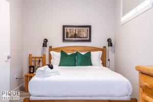 a bedroom with a white bed with green pillows at NEW, Mountain Chic Suite, Whyte Avenue, Netflix, WiFi, Sleeps 6 in Edmonton