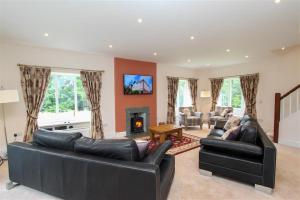 a living room with two leather couches and a fireplace at Elterwater Lodge in Little Langdale