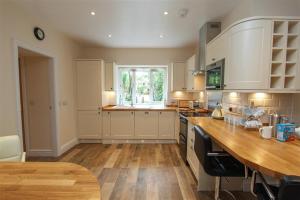 a kitchen with white cabinets and a wooden table at Elterwater Lodge in Little Langdale