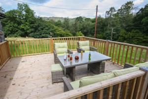 a patio with a table and chairs on a wooden deck at Elterwater Lodge in Little Langdale