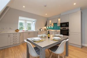 uma cozinha com mesa e cadeiras e uma cozinha com armários brancos em Windermere Suite em Ambleside
