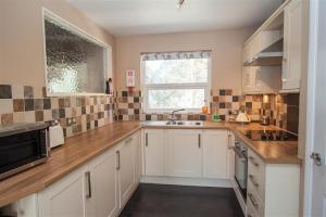 a kitchen with white cabinets and a sink and a window at Mellbreak in Chapel Stile
